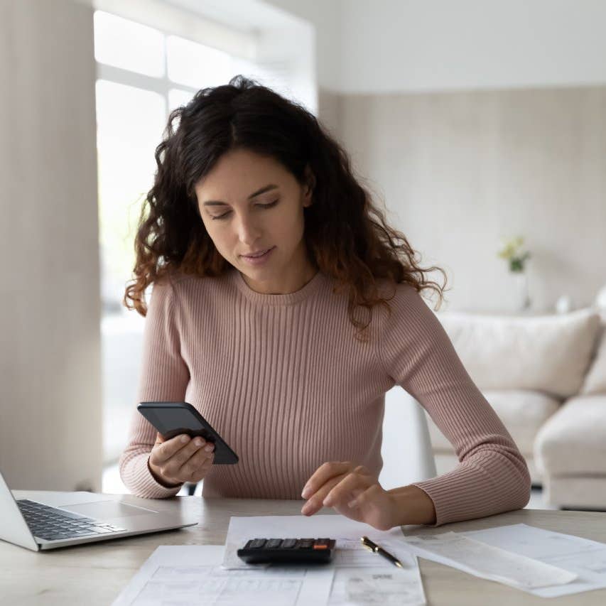 Latino woman calculating her bills in front of a laptop and sitting at a table
