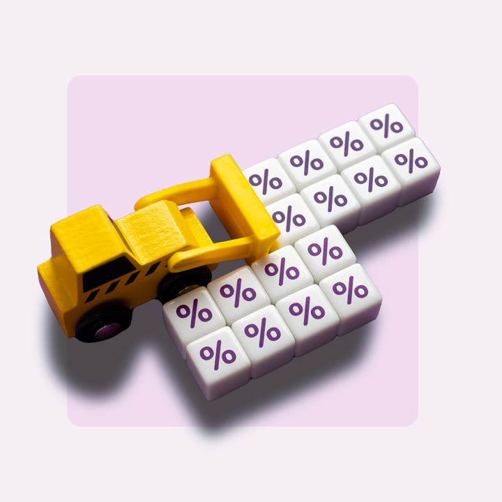 Toy backhoe pushing blocks with percent signs.